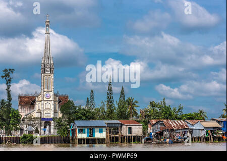 Il Vietnam, il Delta del Mekong, Vinh Long, la chiesa e le case costruite su palafitte dal canale Foto Stock