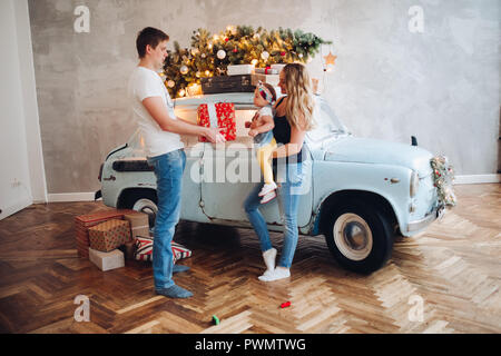 Bel papà Natale dando presente, big red box, per blonde mom e poco carino figlia. Foto Stock