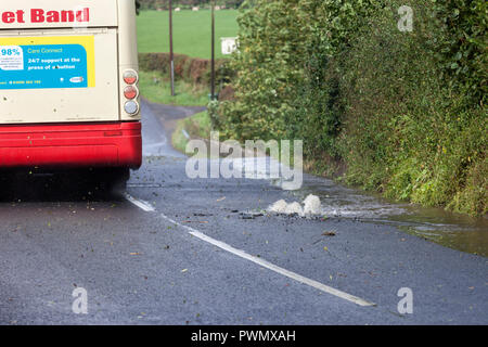 Un Bus azionamento oltre una raffica di acqua nella principale strada, County Durham, Regno Unito Foto Stock
