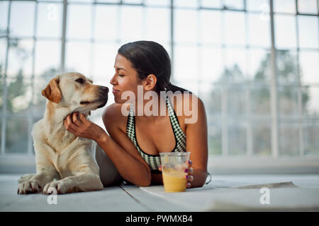 Giovane donna nuzzling il suo cane, mentre la reidratazione con un succo di frutta. Foto Stock