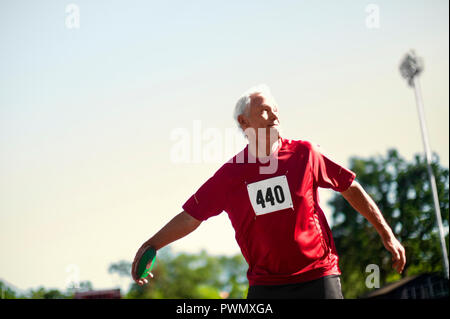 Focalizzato uomo maturo di prendere la mira di un Discus. Foto Stock
