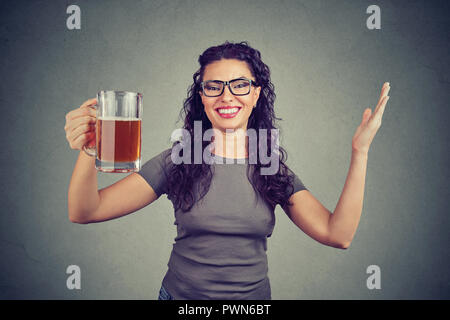 Donna allegra holding tazza di vetro di birra che celebra e sorridente in telecamera Foto Stock