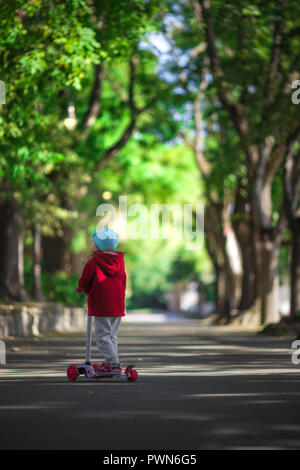 La bambina corse scooter nel parco. Foto Stock