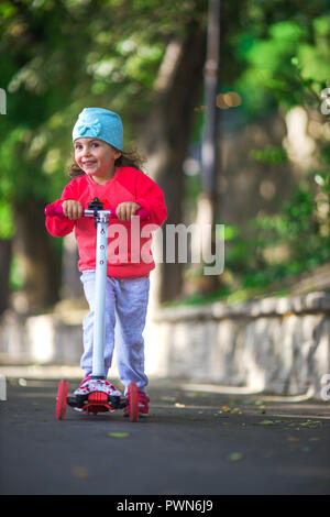 La bambina corse scooter nel parco. Foto Stock