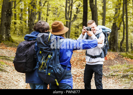 Il gruppo di amici del paese a piedi in una giornata di sole, giovani escursioni in campagna, ragazzo biondo facendo foto per i suoi amici, il concetto di viaggio Foto Stock