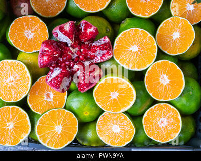 Grande pelato melograno tra tagliato in una metà Arance Limoni con pelle verde, piatto laici vista superiore Foto Stock
