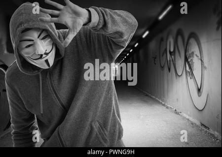 Uomo che indossa una maschera di Guy Fawkes all'entrata di un tummel, anonimo. Foto Stock