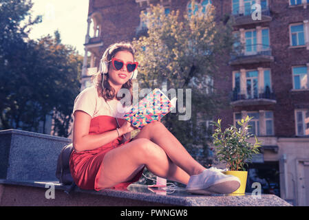 Dai capelli scuri rendendo studente alcune note nel suo notebook che studia chimica Foto Stock