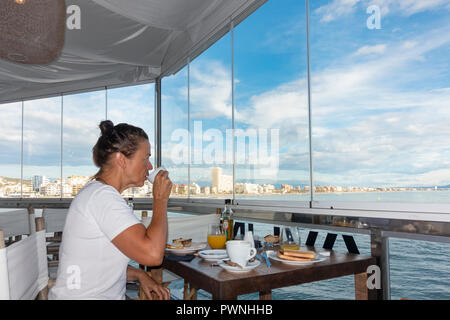 Donna con prima colazione in hotel affacciato sul mare a Peniscola, regione di Valencia, Spagna, Europa Foto Stock