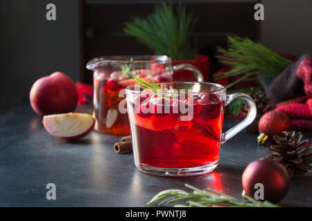 Il Natale di mirtillo palustre e drink apple guarnire con rosmarino e rami di abete su nero. Close up. Xmas drink. Foto Stock