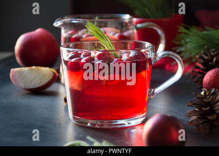 Il Natale di mirtillo palustre e drink apple guarnire con rosmarino e rami di abete su nero. Close up. Xmas drink. Foto Stock