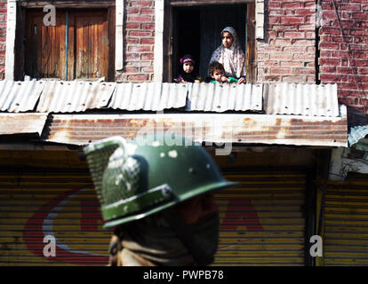 Srinagar Kashmir. 18 ott 2018. Un soldato indiano sta di guardia come figli del Kashmir guardando sulla finestra della loro casa durante il coprifuoco simili restrizioni in parti della valle .Il Giunto resistenza Leadership (JRL), un conglomerato separatista guidato da Syed Ali Geelani, Mirwaiz Umer Farooq e Muhammad Yasin Malik, chiamato l'arresto contro l'uccisione di Lashkar-e-Taiba (LET) commander,Mehrajudd in Bangroo, suo associare Faiz Ahmad Waza e Rayees Ahmad in uno scontro a fuoco il mercoledì a Srinagar's Fateh Kadal area.©Sofi Suhail/Alamy Live News Foto Stock