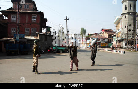 Srinagar Kashmir. 18 ott 2018. Un soldato indiano sta di guardia come latte Kashmir uomo trasporta il latte ,durante il coprifuoco simili restrizioni in parti della valle .Il Giunto resistenza Leadership (JRL), un conglomerato separatista guidato da Syed Ali Geelani, Mirwaiz Umer Farooq e Muhammad Yasin Malik, chiamato l'arresto contro l'uccisione di Lashkar-e-Taiba (LET) commander,Mehrajudd in Bangroo, suo associare Faiz Ahmad Waza e Rayees Ahmad in uno scontro a fuoco il mercoledì a Srinagar's Fateh Kadal area.©Sofi Suhail/Alamy Live News Foto Stock