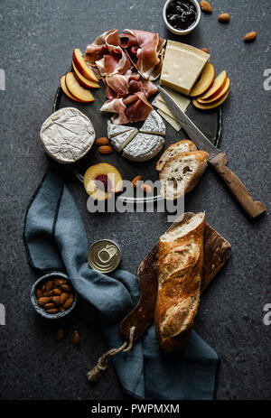 Formaggio e prosciutto piastra con parmigiano, camamber, formaggio di capra, prosciutto, baguette e spuntini. Vista aerea, sfondo scuro Foto Stock