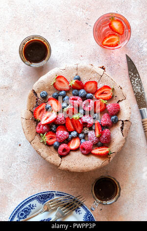 Meringa al cioccolato torta guarnita con frutta fresca sul tavolo Foto Stock