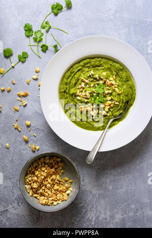 Zuppa di broccoli in una ciotola con un cucchiaio e una ciotola di frantumati Noci di acagiù. Foto Stock