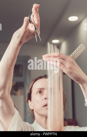 Parrucchiere è il taglio di capelli lunghi biondi nel salone di parrucchiere Foto Stock