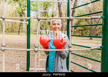 Ritratto di felice fit donna Senior con guanto di boxe in palestra esterna dell'abbigliamento sportivo. Active Anziani Lifestyle Fitness Foto Stock