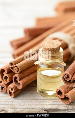 Olio di cannella e bastoncini di cannella sul pannello di legno Foto Stock