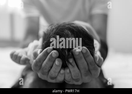 Padre è il ritegno della testa del suo neonato in mani, vicino. Foto Stock