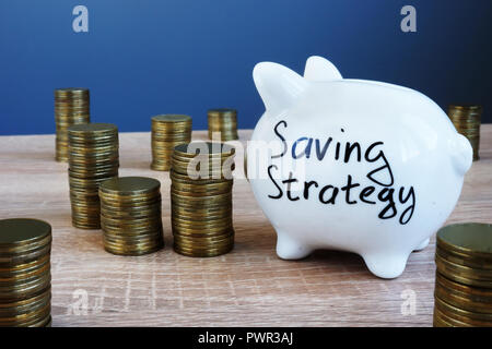 Strategie di risparmio scritto su un salvadanaio e denaro. Foto Stock