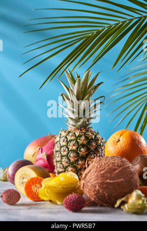 Mix esotico da maturi frutti freschi - pineaple, dragon frutta, mango, cocco, kiwi, carambole, litchi sul grigio di un tavolo di pietra su un blu. Foto Stock