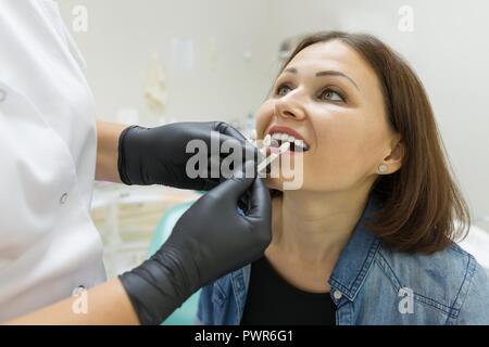 Donna adulta seduto in poltrona del dentista in clinica e la preparazione per la procedura. Medicina e odontoiatria e concetto di assistenza sanitaria Foto Stock