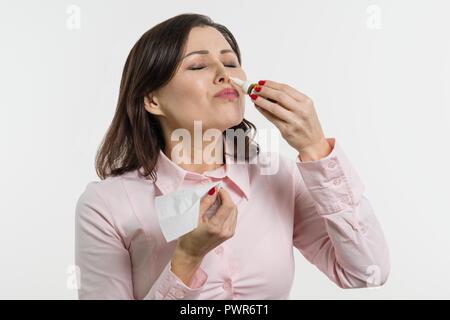 Donna gocciolamenti gocce per il naso. Sfondo bianco Foto Stock