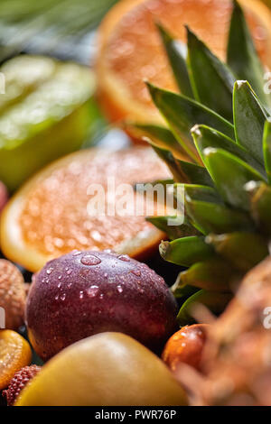 Tropical fresco di sfondo con Esotici frutti della passione in goccioline di acqua e Verde foglie di ananas. Sallow profondità di campo. Foto Stock