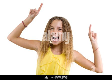 Felice bionda con capelli ricci, teen girl puntando il suo dito indice, indicando copia spazio bianco sulla parete vuota per i tuoi contenuti o informazioni, isola Foto Stock