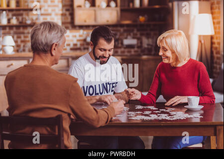 Uomo gioioso puzzle mettendo insieme con i pensionati Foto Stock