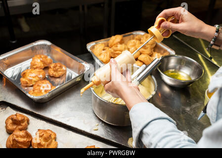 Torte di panna in mani femminili in cucina Foto Stock