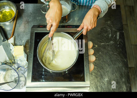 Le mani delle donne con una frusta spostare la crema in attesa Foto Stock