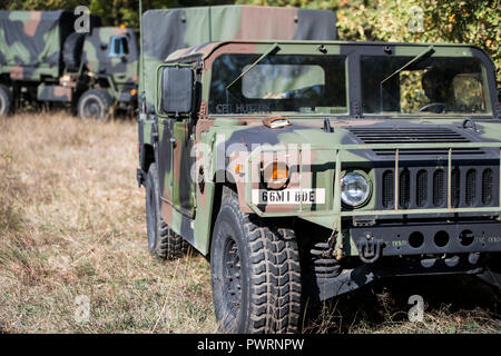 Una elevata mobilità multiuso di veicolo su ruote (HMMWVA 'Humvee') veicolo siede dormienti. Nel frattempo preparare i soldati delle difese di protezione attorno al loro perimetro poco prima di un attacco simulato su una posizione difensiva durante montato e smontato le operazioni di formazione presso il "dune di sabbia" area formazione vicino a Mainz, Germania. Foto Stock