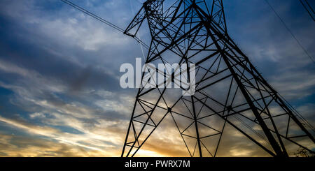 Alta torre di acciaio di supporto cavi elettrici. Visualizzazione di un'alta torre in acciaio sotto il cielo nuvoloso scuro. La torre contiene fino cavi elettrici utilizzati per l'impianto elettrico Foto Stock