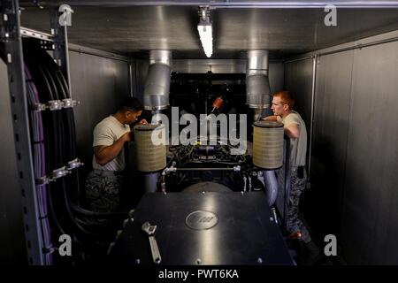 Il personale Sgt. Justin Tayamen e Staff Sgt. Bryce Skawski, 786th civile squadrone tecnico di produzione di energia elettrica degli artigiani, discutere i piani per un generatore di manutenzione preventiva su ispezione Ramstein Air Base, Germania, 27 giugno 2017. Il generatore del sistema fornisce apparecchiature di back-up automatico alimentazione elettrica a Ramstein più critical facilities. Foto Stock