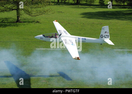 Swift S-1 glider di Twister Team acrobatico volato da Guy Westgate tenendo spenta sotto il traino a Henham Park nella campagna di Suffolk. Fumo dal piano di traino Foto Stock