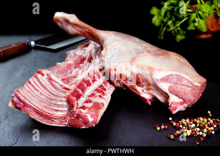 Fresco e carne cruda. Nervature e costolette di maiale non cotte, pronto per grill e barbecue sul nero ardesia sfondo Foto Stock