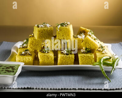 DHOKLA KHAMAN con chutney di coriandolo e peperoncini verdi/ una pasta cotta a vapore costituito da farina di GRAM Foto Stock