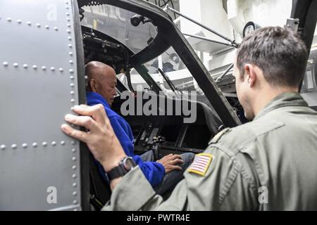 Oceano Pacifico (20 giugno 2017) Lt. La Cmdr. Andrew Poreda, un pilota in carica di elicottero imbarcato Maritime Strike Squadron (HSM) 78, consente agli amici e familiari dei membri dell'equipaggio a bordo Arleigh Burke-class guidato-missile destroyer USS Wayne E. Meyer (DDG 108) per sedersi nella cabina di pilotaggio di un MH-60R Sea Hawk elicottero attaccato al HSM-78 durante una tigre cruise tour. Gli Stati Uniti Marina ha pattugliato il Indo-Asia-Pacifico di routine per più di 70 anni regionale di promozione della pace e della sicurezza. ( Foto Stock