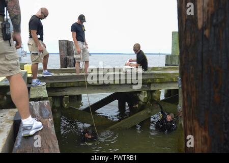 Stati Uniti Army divers assegnato all'ingegnere 74Dive distacco, 92Eng. Battaglione riferire i risultati mentre si ispezionano il terzo porto pontili durante una missione di immersioni a base comune Langley-Eustis, Va., 20 giugno 2017. Mentre si ispezionano i piloni, i subacquei determinerà se il team ha le risorse per risolvere il danno o se esse sono destinate ad allogare il lavoro. Foto Stock