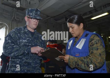 Oceano Pacifico (21 giugno 2017) Combattere l'assistente cargo Gunnery Sgt. Carmen Christman, destra, assiste il marinaio Jackson Berg nel controllo a bordo del Wasp-classe assalto anfibio nave USS Essex (LHD 2). L'Essex è in corso di conduzione ponte di volo certificazioni e prove in mare al largo della costa della California del Sud. ( Foto Stock