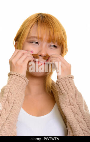 Giovane donna asiatica annusare i suoi capelli mentre guarda lontano Foto Stock