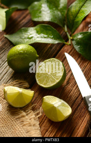 Lime frutti con foglie su un tavolo di legno - Frutta tropicali con proprietà antiossidanti - primo piano Foto Stock