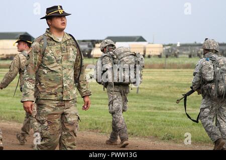 Army Sgt. Jonathan Youngbear, un supporto di ingranaggio cilindrico con Bravo truppa, 1° Stormo, 113reggimento di cavalleria, 2° Brigata Team di combattimento, 34a divisione di fanteria, guarda indietro al ruck marzo colonna per offrire incoraggiamento a spur ride candidati durante la formazione annuale presso il Camp Ripley, Minn., il 22 giugno 2017. Foto Stock