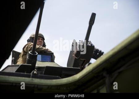 Un Marine si siede in cima alla torretta di un assalto anfibio veicolo come si fa il suo modo di eseguire il backup di gamma per essere ispezionato a Camp Lejeune, N.C., 27 giugno 2017. I marines effettuato riprese in tabelle di AAV a rimanere qualificato con il veicolo in sistemi d'arma. Il Marine è con il secondo assalto anfibio battaglione. Foto Stock