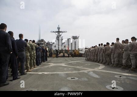 Mare Arabico (Luglio 1, 2017) Marines e marinai in possesso di una formazione a bordo della USS Carter Hall (LSD 50) per un giorno di indipendenza rispetto, 1 luglio 2017. Ventiquattresimo Marine Expeditionary Unit è attualmente distribuito negli Stati Uniti Quinta Flotta area di operazioni a sostegno della sicurezza marittima operazioni destinate a rassicurare gli alleati e partner e preservare la libertà di navigazione e il libero flusso di commercio nella regione. Foto Stock