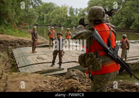 Un soldato assegnato al trentasettesimo reggimento ingegnere, Ungherese Defence Force getta un cavo a un soldato assegnato alla brigata 837th Engineer battaglione, U.S. Esercito Nazionale Guardia da Wooster, Ohio per ancorare il PMP galleggiante ponte alla riva del fiume Mosoni-Duna a Gyor, Ungheria durante l'esercizio Szentes Ax 17 Luglio 4, 2017. La nazionale ungherese di esercizio avviene 26 Giugno-luglio 7 per consentire al custode di Saber 17 effettuando il bridging tattico e la acque che attraversano le operazioni per 2d reggimento di cavalleria, U.S. Esercito la libertà di movimento dalla stazione di casa in Ungheria e in molte operazioni congiunte area località. Foto Stock