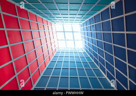 Prospettiva astratta della lobby verticale soffitto con lucernario e forte la geometria e la simmetria e colori drammatici come sfondo Foto Stock