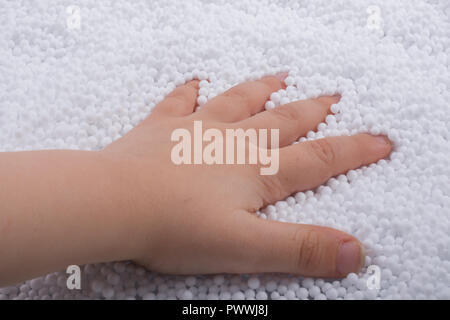 Bimbi in mano di polistirene bianco le sfere di schiuma come sfondo Foto Stock